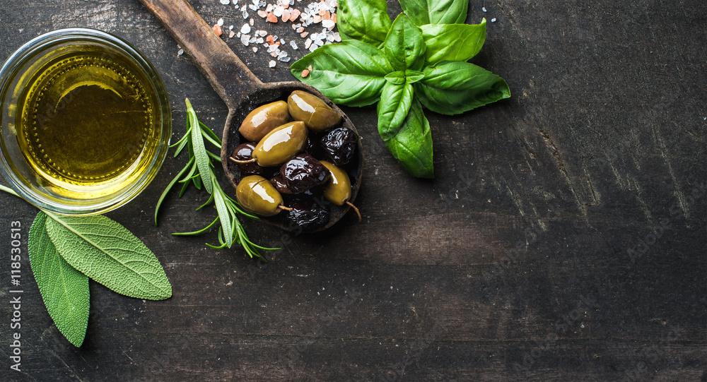 绿色和黑色的地中海橄榄放在旧烹饪勺里，配橄榄油和香草，配深色乡村风味
