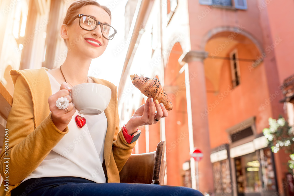一名年轻女子在博洛尼亚街头的咖啡馆享用意大利羊角面包和咖啡早餐