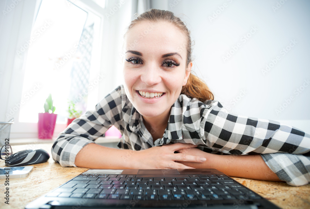 微笑的女人在家庭办公室使用笔记本电脑，从网络摄像头观看