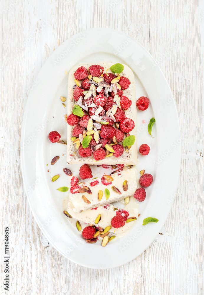 Homemade semifreddo with pistachio and raspberry in oval dish over old white painted wooden backgrou