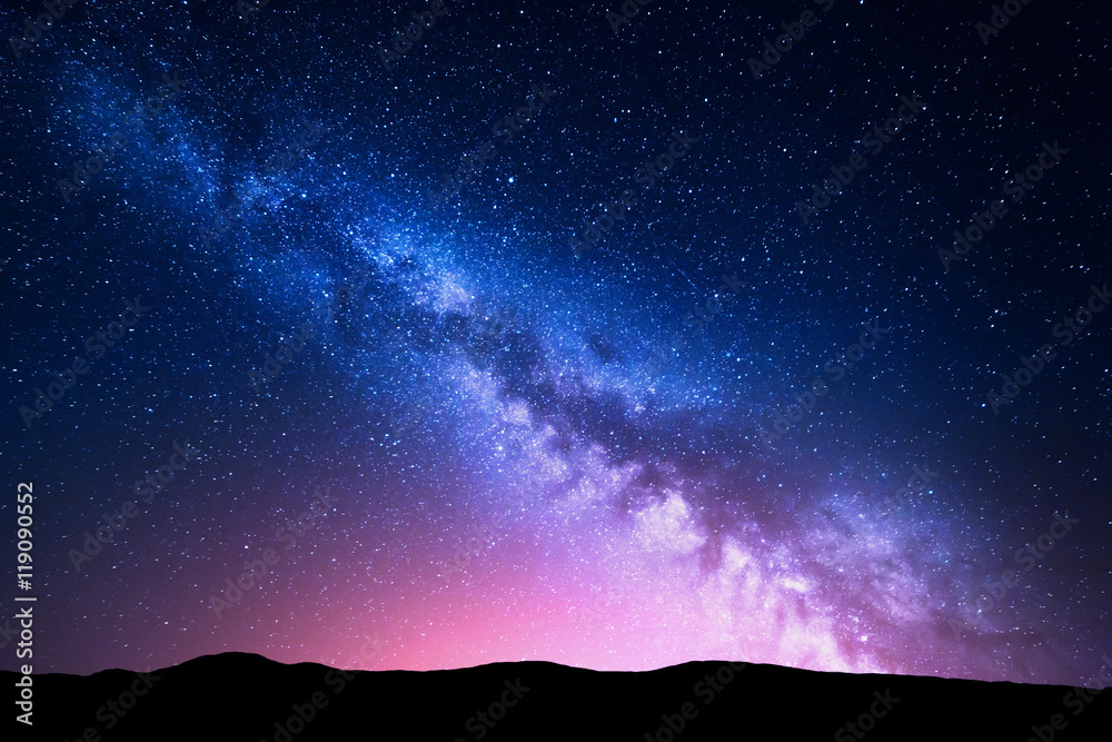 银河系和山上的粉红色光芒。夜晚色彩缤纷的风景。
