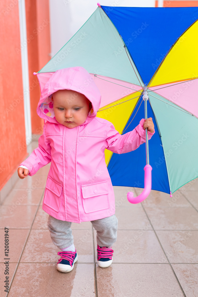 打着五颜六色雨伞的小女孩在雨中行走。