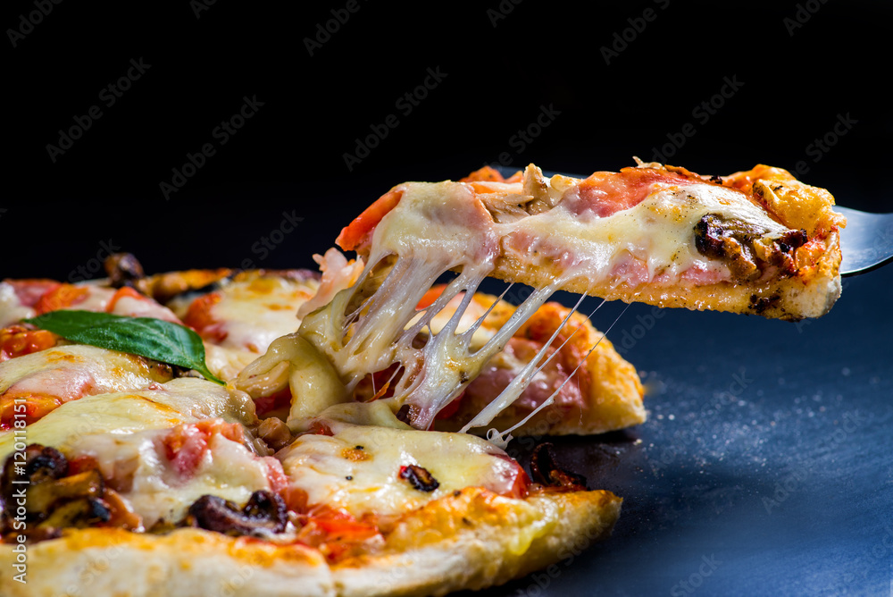 切下一片披萨。融化的奶酪从披萨片上伸出来
