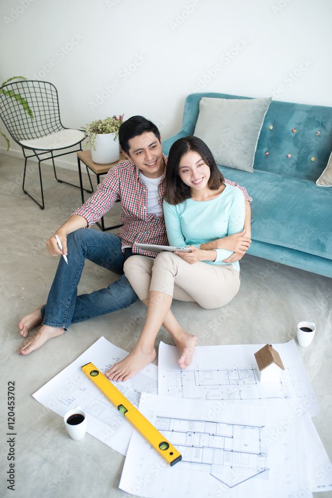 兴高采烈的亚洲夫妇正在看建筑房屋计划