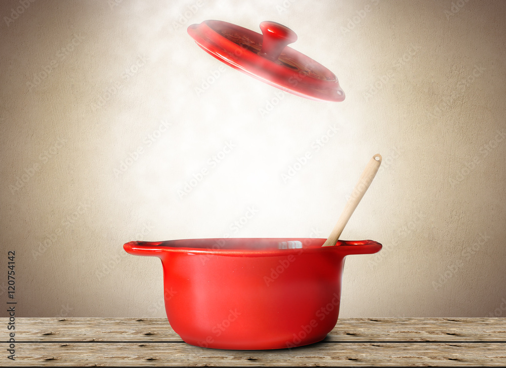 用勺子和叉子盛汤的红色大锅