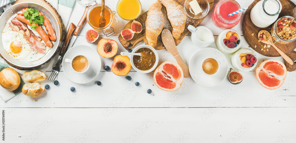 早餐概念食品框架。煎蛋配香肠和培根、面包、羊角面包、果酱、水果、烟熏