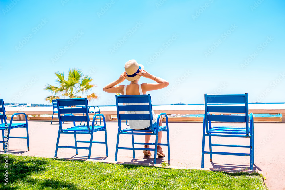 坐在戛纳海滨大道蓝色椅子上的女人。这把椅子是标志性的象征。
