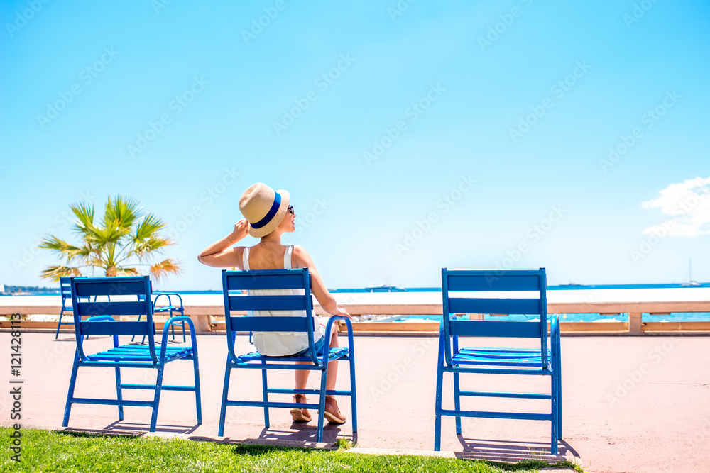 坐在戛纳海滨大道蓝色椅子上的女人。这把椅子是标志性的象征。