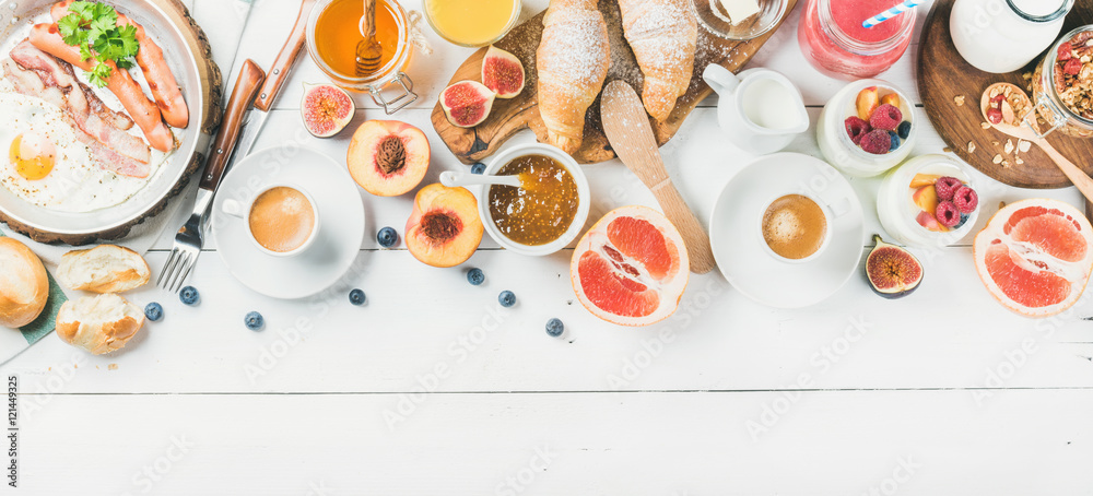 早餐概念食品框架。煎蛋配香肠和培根、面包、羊角面包、果酱、水果、烟熏
