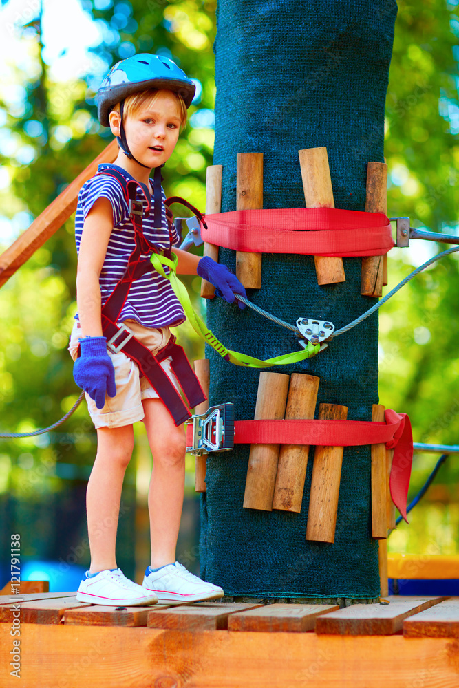 小男孩在树林中穿过电缆路线，在冒险公园进行极限运动