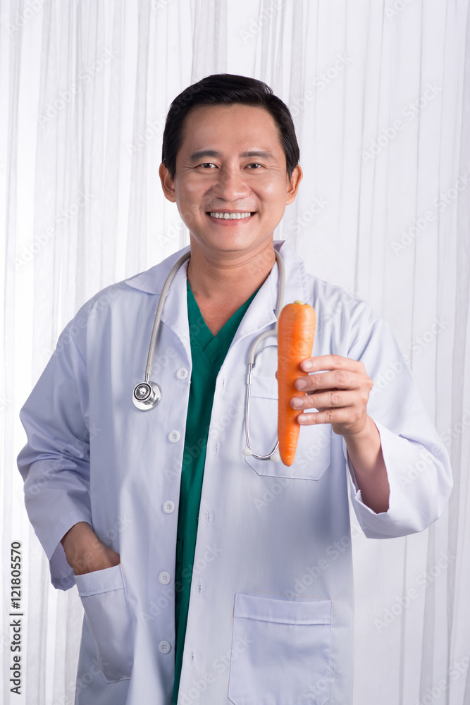 护士或男医生给胡萝卜微笑。健康护理理念