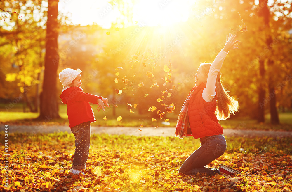 快乐的家庭母亲和小女孩玩耍并扔树叶