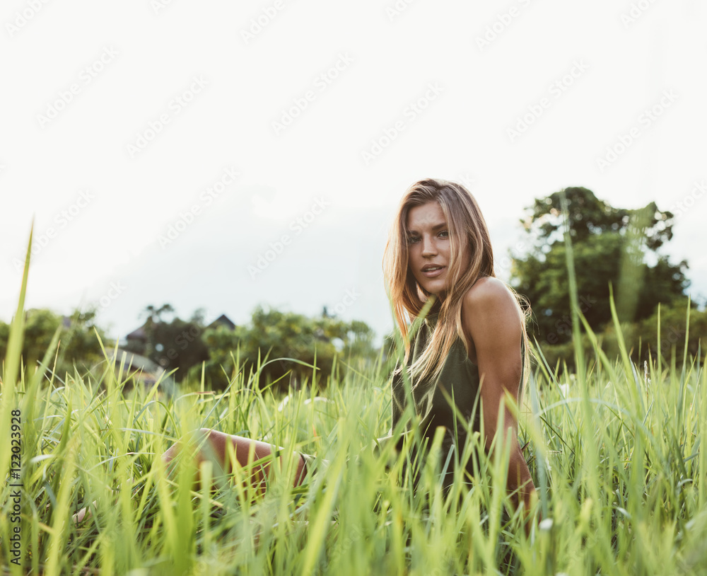 美丽的年轻女子坐在高高的草地上