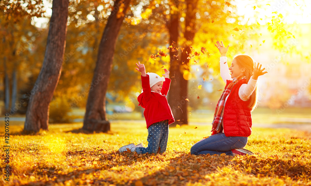 幸福的家庭母亲和小女孩在一起玩耍并扔树叶
