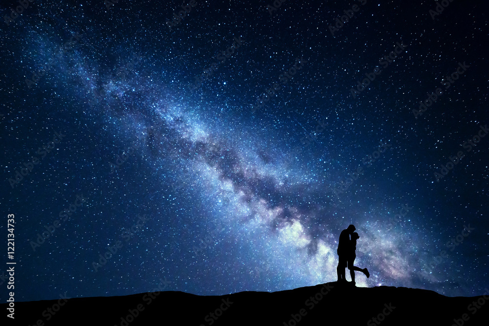Milky Way. Night landscape with silhouettes of hugging and kissing man and woman on the mountain. Sk