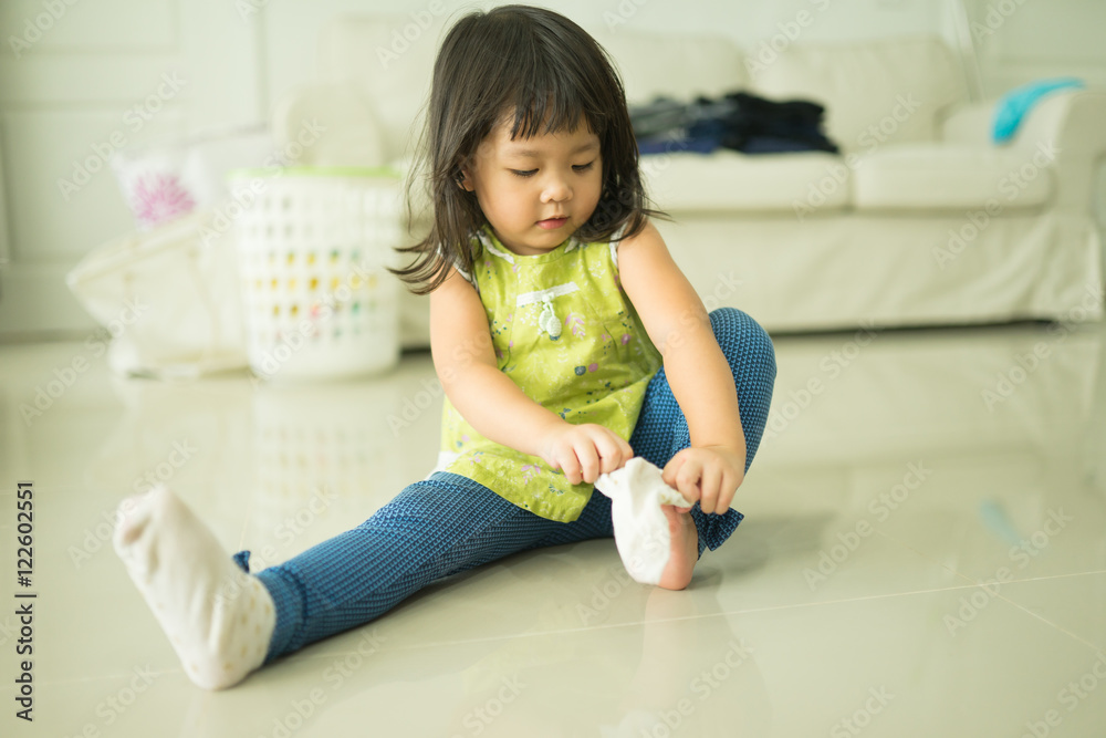 可爱的亚洲小女孩试图穿上袜子。儿童发育。