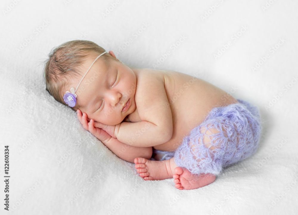 可爱的睡着的新生儿，手放在头下，穿着紫色内裤