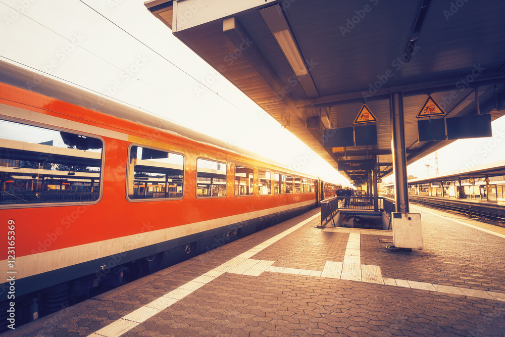 日落时分，高速红色列车在火车站台上。有通勤列车的火车站。铁路