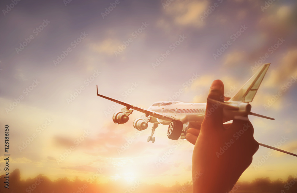 男子手持玩具飞机和日落背景的特写照片