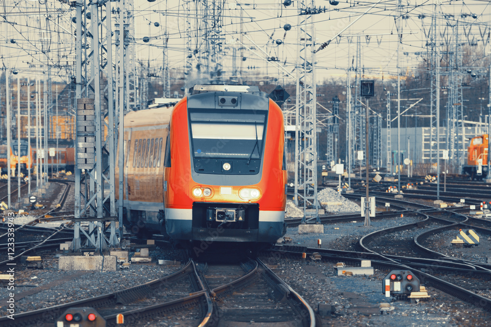 铁路上的现代橙色通勤列车。欧洲的火车站。复古色调的铁路。