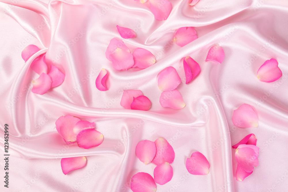 柔软的粉色丝绸面料上的甜美粉色玫瑰花瓣，浪漫和爱情卡片概念