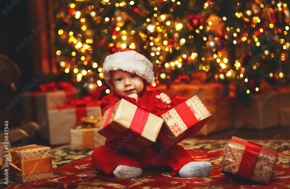 带礼物的圣诞树旁的快乐宝宝