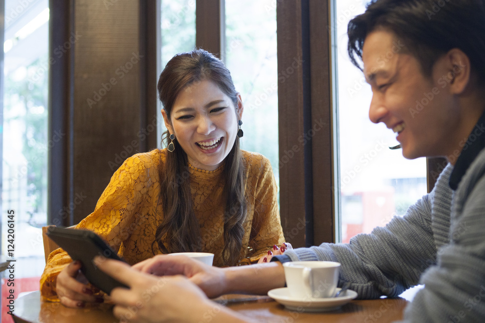年轻夫妇一起在咖啡馆看平板电脑