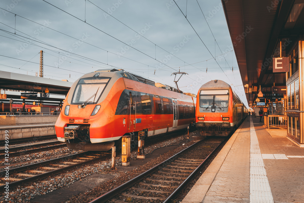 火车站台上的高速橙色通勤列车。美丽的火车站，现代化的交通工具