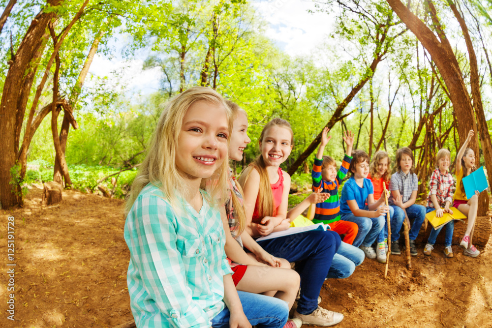 快乐的孩子们坐在夏令营的木头上