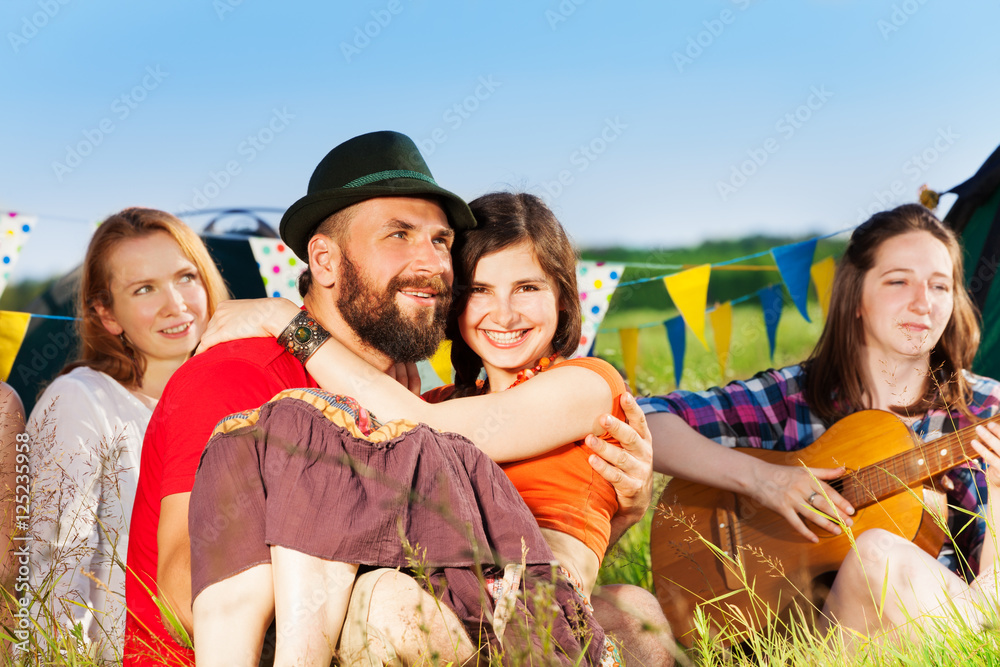 年轻幸福的情侣坐在露营地的草地上