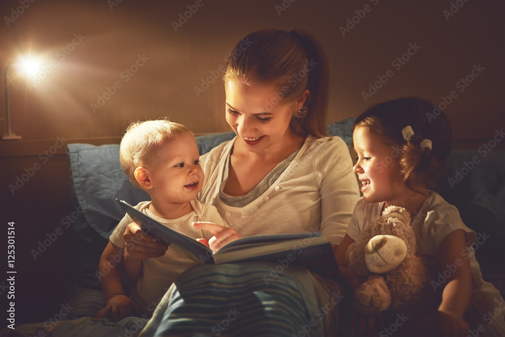 幸福的家庭母亲和孩子在床上看书