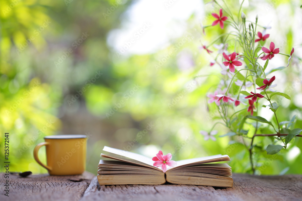 Notebook and yellow coffee cup with flowers  on wooden table