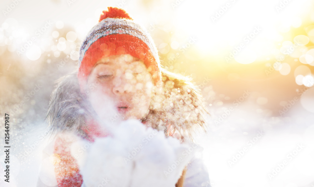 快乐的女人在冬天的大自然中吹雪