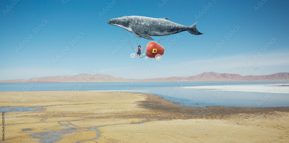 旅行理念。鲸鱼漂浮在天空中，用梦幻苹果自行车载着一个快乐的妹妹。