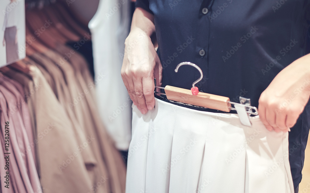 close up hand of woman trying to wear clothes in clothing store