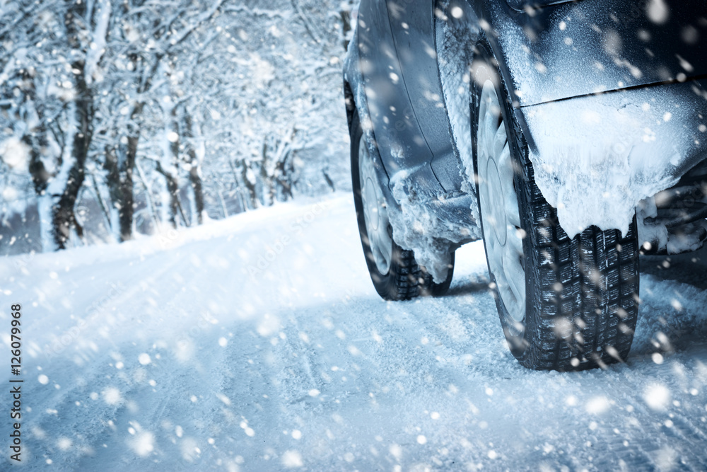 冬季道路上的汽车轮胎被雪覆盖。早上下雪时，车辆在雪地小巷上行驶