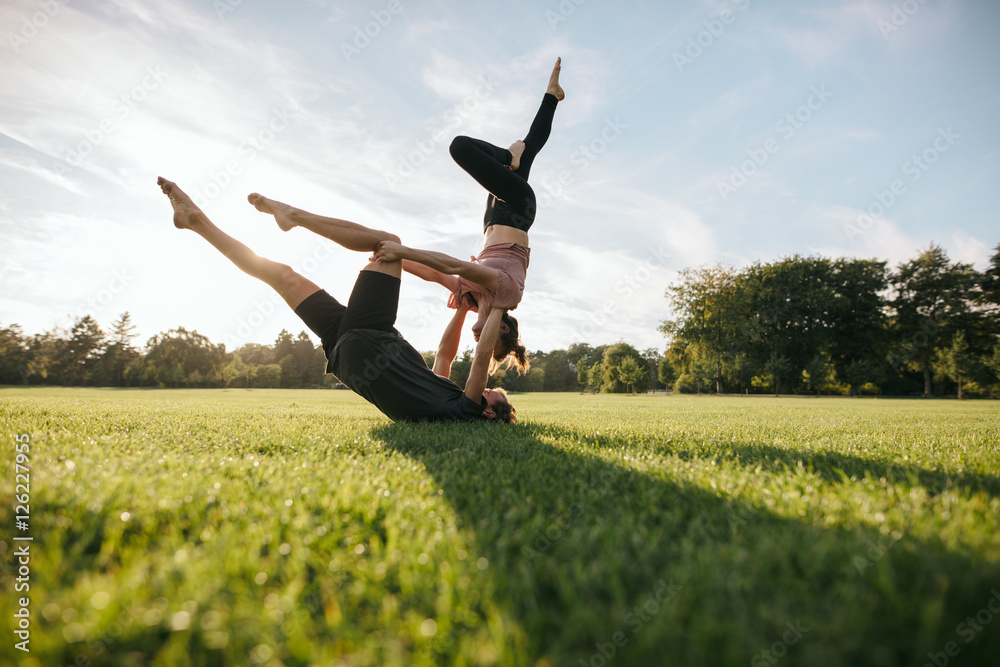 健康的年轻情侣在草地上做高空瑜伽