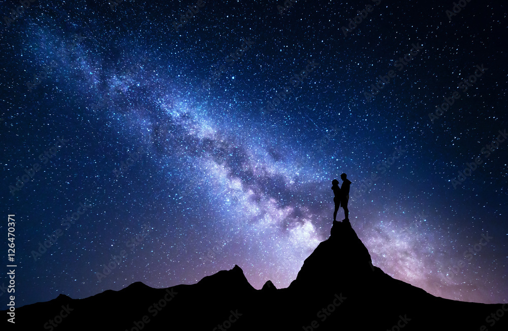 Milky Way with silhouette of people. Night landscape with starry sky. Standing man and woman on the 