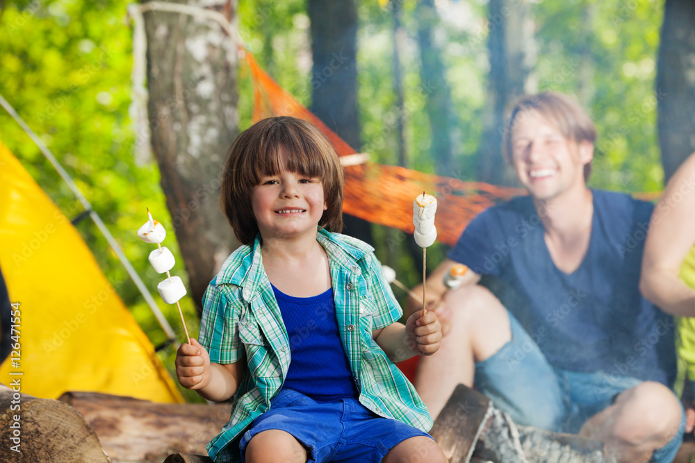 快乐微笑的男孩在露营地吃棉花糖