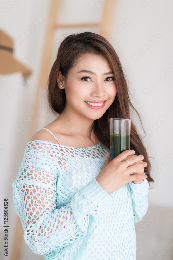 微笑的年轻亚洲女人喝绿色新鲜蔬菜汁o