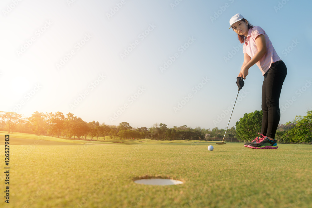 亚洲女子高尔夫球手将高尔夫球放在果岭上，高尔夫球博士