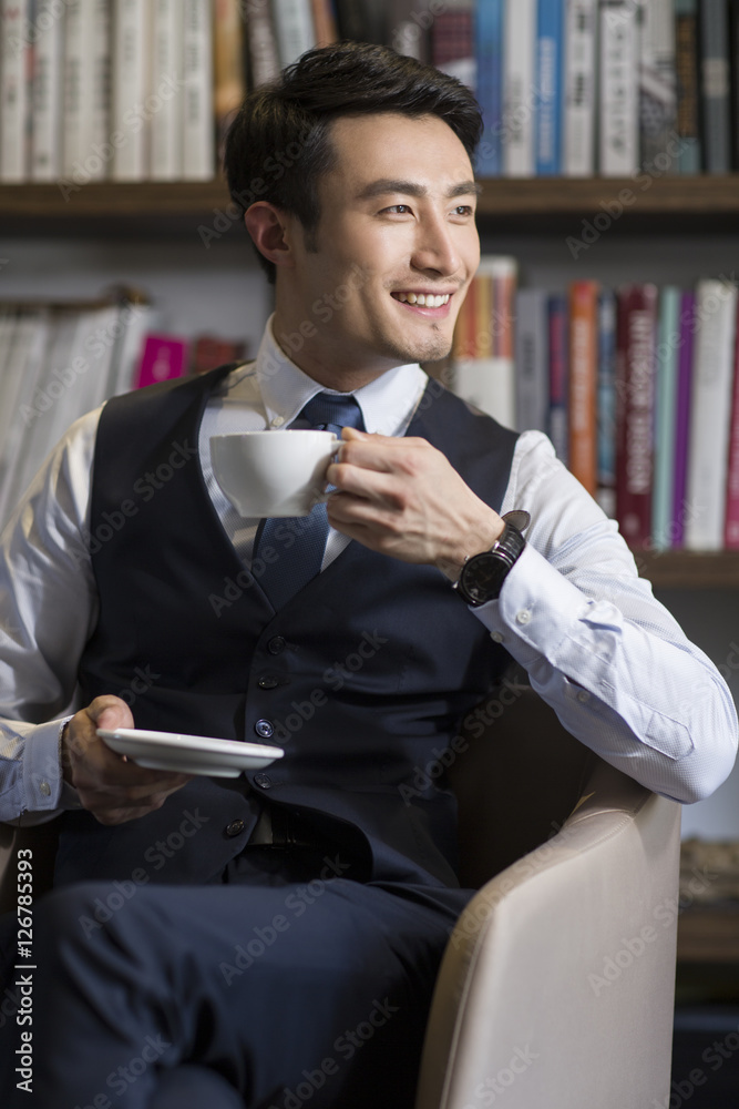Young businessman drinking coffee in his study