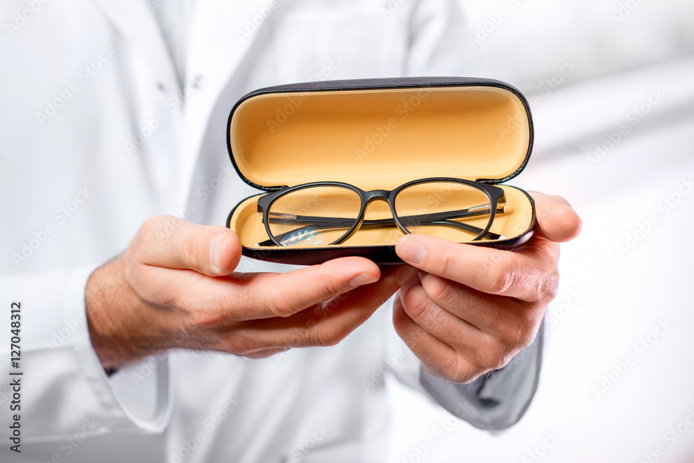 身穿制服的眼科医生拿着黄色的眼镜进行观察。特写镜头聚焦在眼镜上