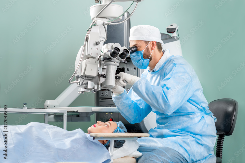 外科医生在手术室看着女性患者眼睛的显微镜