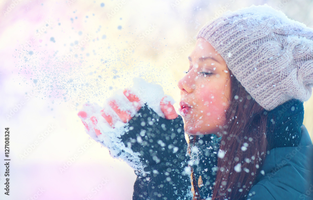 美丽的冬季女孩在霜冻的冬季公园吹雪