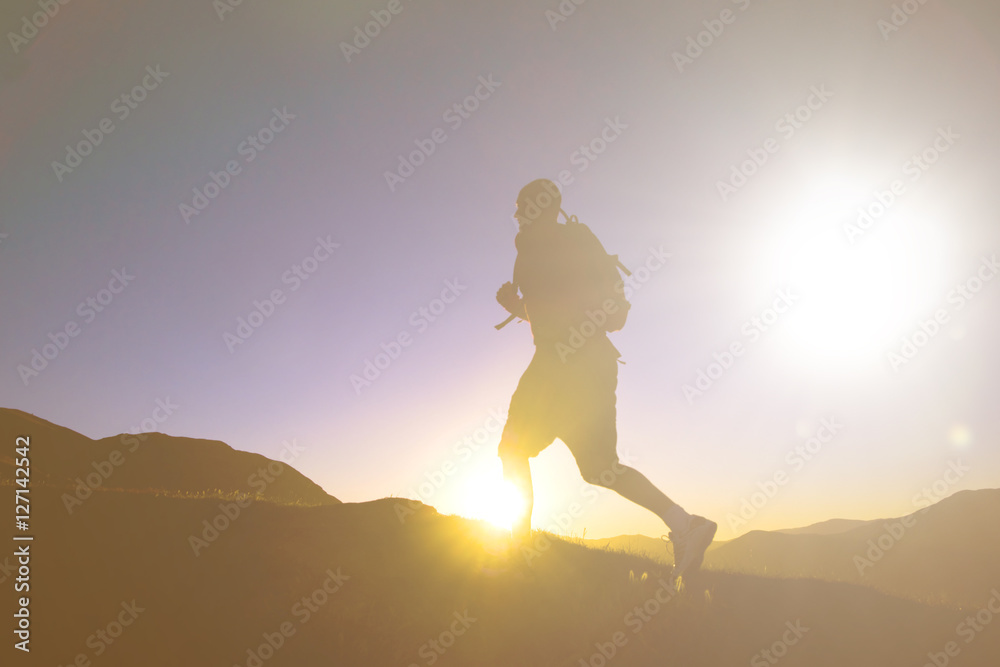 在日落中与山脉一起奔跑的男人剪影