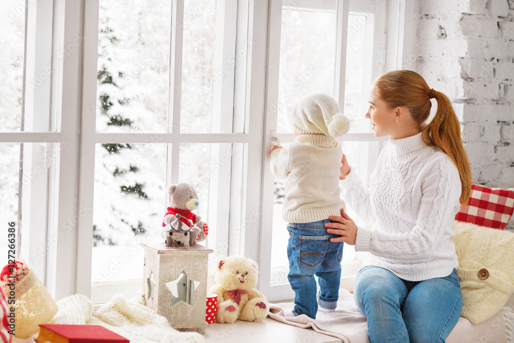 幸福的家庭母亲和婴儿在窗外寻找冬天的克丽