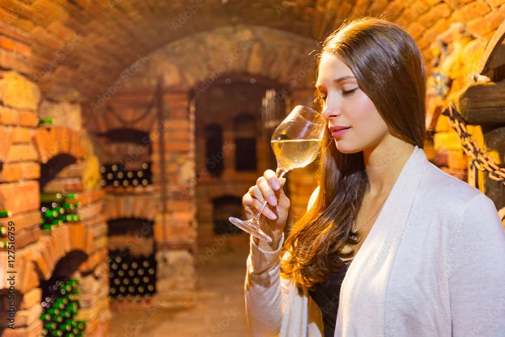 Young brunette woman degusting wine in cellar