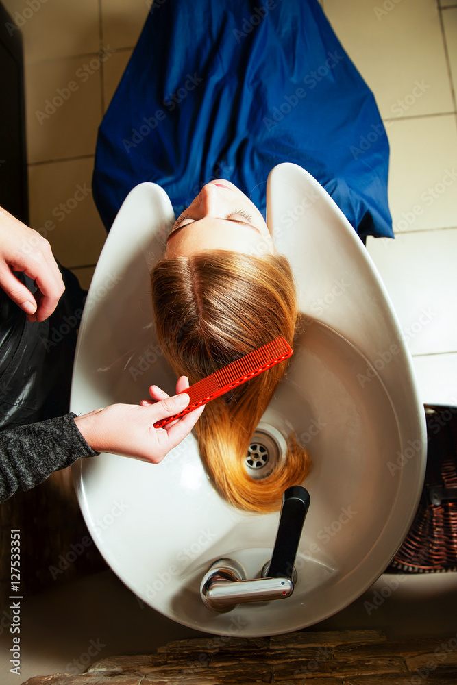 理发师在沙龙为年轻女性洗头。