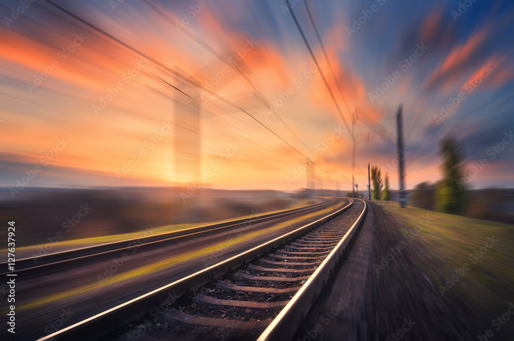 日落时铁路在运动。印第安纳州彩色蓝天背景下的火车站具有运动模糊效果